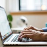 Primer plano de manos masculinas escribiendo en una computadora portátil, representando el trabajo digital o marketing online.