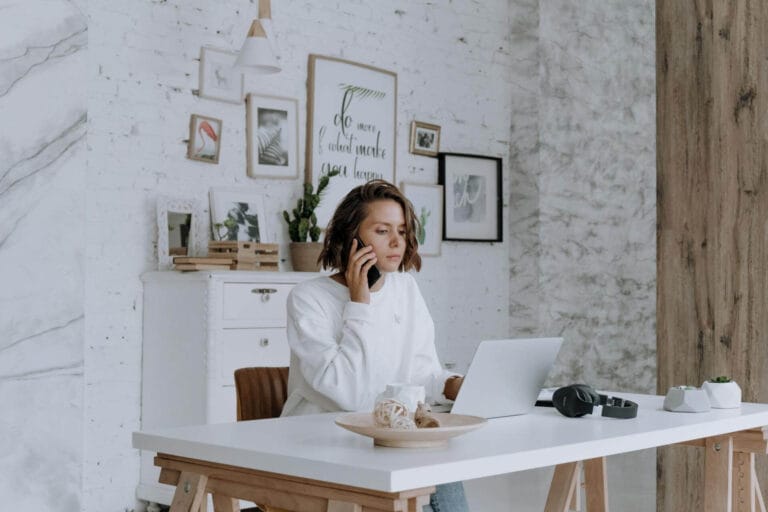 Guía realista sobre cómo empezar un negocio de dropshipping, mostrando el escritorio de un emprendedor con un portátil, libreta y cajas de envío.