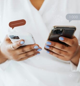 Manos sosteniendo dos smartphones con iconos de burbujas de chat y likes, simbolizando el UGC y la prueba social.